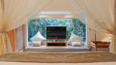 a bedroom with a bed with a large window at Jepun Villa by Betterplace in Seminyak