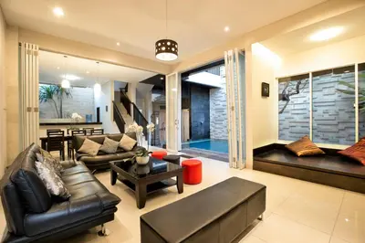 a living room with leather furniture and a large window at InKuta Residence and Villa in Seminyak