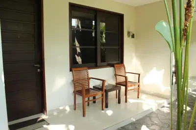 three chairs and a table in a room with a window at InKuta Residence and Villa in Seminyak