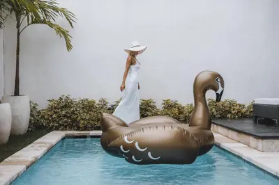 a woman in a white dress standing next to a swimming pool at Villa Manis Kecil in Seminyak