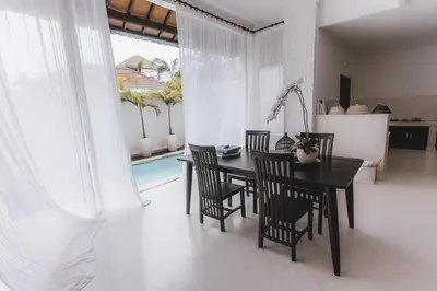 a dining room with a black table and chairs at Villa Manis Kecil in Seminyak