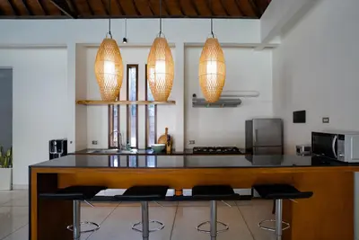 a kitchen with a counter with chairs and lights at Villa Duadewi 3BR in the Heart of Seminyak by Santi Management in Seminyak