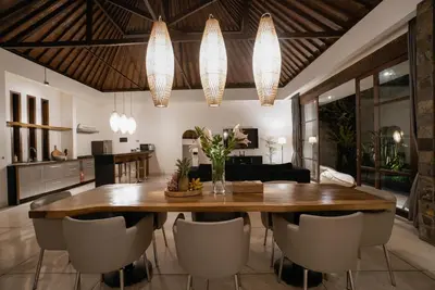 a kitchen and living room with a wooden table and chairs at Villa Duadewi 3BR in the Heart of Seminyak by Santi Management in Seminyak