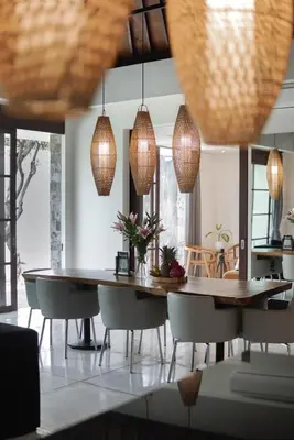 a dining room with a table and chairs and pendant lights at Villa Duadewi 3BR in the Heart of Seminyak by Santi Management in Seminyak