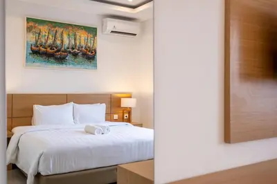 a bedroom with a bed and a painting on the wall at Adikara Apartment by Betterplace in Canggu