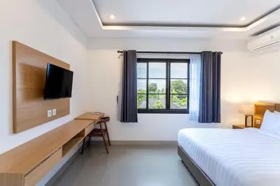 a bedroom with a bed and a desk and a television at Adikara Apartment by Betterplace in Canggu