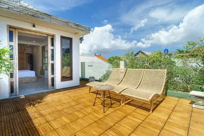 a wooden deck with two chairs and a table at Villa Nirvana Seminyak in Seminyak