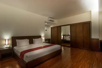 a bedroom with a large bed and wooden floors at Seminyak Square Hotel And Villas in Seminyak