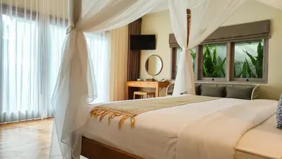 a bedroom with a large bed with curtains and a window at Seminyak Square Hotel And Villas in Seminyak