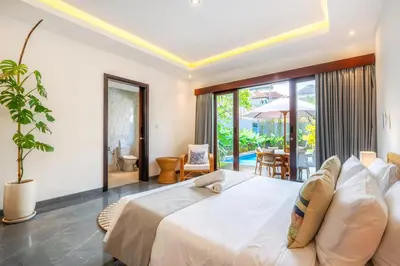 a bedroom with a large white bed and a patio at Villa Taj - Luxury 3-bedroom Pool Villa Near Seminyak in Kerobokan