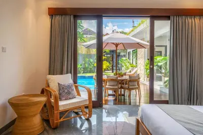 a hotel room with a bed and a table with an umbrella at Villa Taj - Luxury 3-bedroom Pool Villa Near Seminyak in Kerobokan
