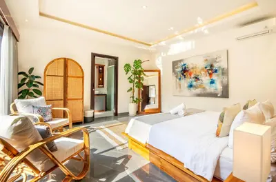 a bedroom with a bed and chairs in a room at Villa Taj - Luxury 3-bedroom Pool Villa Near Seminyak in Kerobokan
