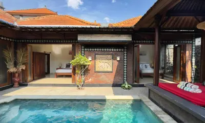 a villa with a swimming pool in front of a house at Villa Mutti in Seminyak
