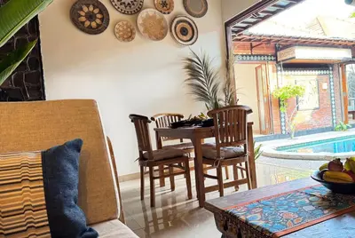a living room with a table and chairs and a pool at Villa Mutti in Seminyak
