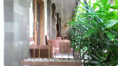 a porch with a bunch of chairs and plants at Kubu Carik in Legian