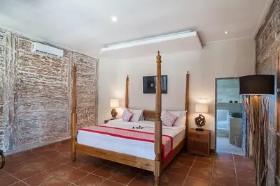 a bedroom with a large bed and a brick wall at Villa Toto Seminyak in Seminyak