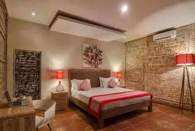 a bedroom with a bed and a desk and a lamp at Villa Toto Seminyak in Seminyak