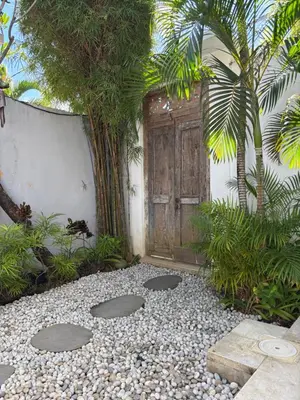 a garden with a door and some trees and gravel at AMAZING 1 BR Villa Private Pool walk to beach in Seminyak