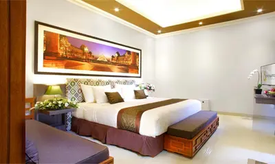 a bedroom with a large bed and a painting on the wall at The Banyumas Suite Villa Legian in Legian