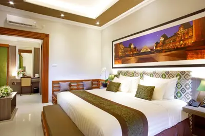 a bedroom with a large white bed with a large painting on the wall at The Banyumas Suite Villa Legian in Legian