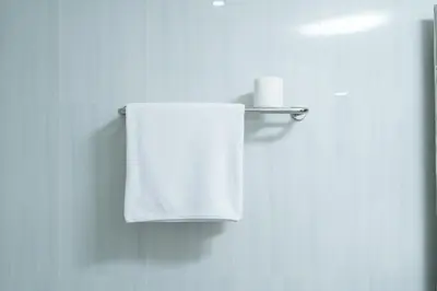 a white towel hanging on a towel rack in a bathroom at The Kifaraju Nusa Dua Bali in Nusa Dua
