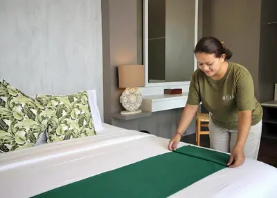 a woman is making a bed in a hotel room at Villa Maisha by REJA Villas in Nusa Dua