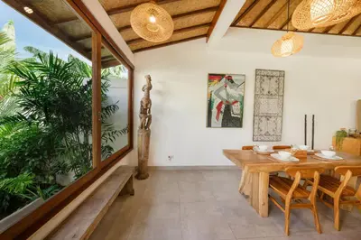 a dining room with a wooden table and chairs at Villa Kepompong Seminyak - 1BR Private Pool Villa in Seminyak