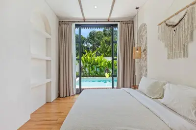 a bedroom with a bed and a view of a pool at Mediterranean 2BR Villa Ellure Ember with Pool & Lush Garden in Jimbaran