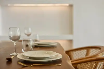 a wooden table with plates and wine glasses on it at Mediterranean 2BR Villa Ellure Ember with Pool & Lush Garden in Jimbaran