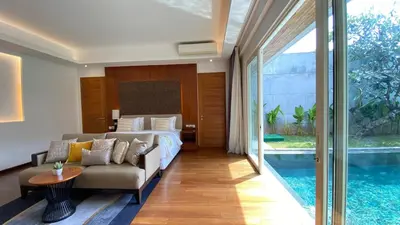 a bedroom with a bed and a couch and a pool at YY Villa Seminyak - 4BR Luxury Private Villa in Seminyak