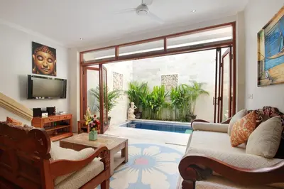 a living room with a couch and a tv and a pool at Legian Blue Ocean Villa in Seminyak