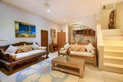 a living room with two couches and a staircase at Legian Blue Ocean Villa in Seminyak