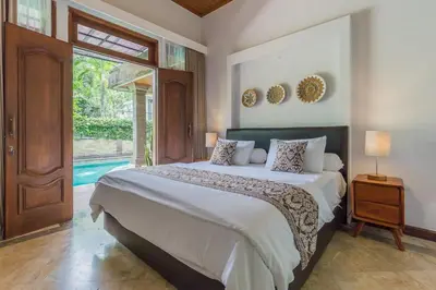 a bedroom with a large bed and a large window at Castila Saraswati - Tranquil 4BR Villa in Kayu Aya in Seminyak