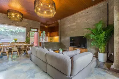 a living room with a large couch and a table at Castila Saraswati - Tranquil 4BR Villa in Kayu Aya in Seminyak