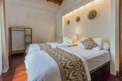 a bedroom with two beds and a mirror on the wall at Castila Saraswati - Tranquil 4BR Villa in Kayu Aya in Seminyak