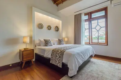 a bedroom with a large bed and a window at Castila Saraswati - Tranquil 4BR Villa in Kayu Aya in Seminyak