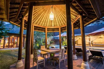 a pavilion with a table and chairs and a pool at Villa Tantri in Kerobokan