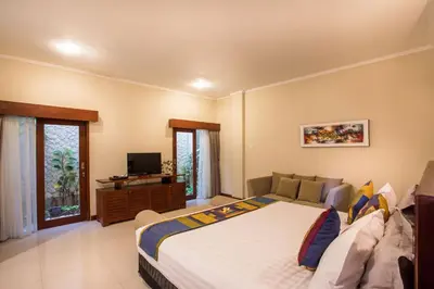 a bedroom with a bed and a couch and a television at Villa Tantri in Kerobokan