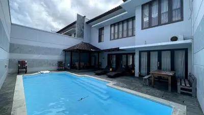 a swimming pool in front of a house at Bali mansion kuta in Legian