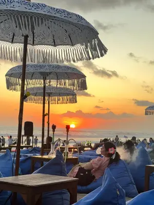 a woman sitting on the beach under an umbrella at Blue Diamond Residenses Seminyak in Seminyak