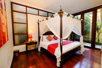 a bedroom with a canopy bed in a room with windows at Villa Jepun Seminyak in Canggu