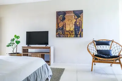a bedroom with a bed and a tv and a chair at Canggu Art Loft - Luxury Stay with Berawa View 2BDR in Canggu