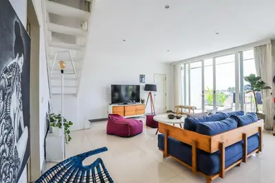 a living room with a blue couch and a tv at Canggu Art Loft - Luxury Stay with Berawa View 2BDR in Canggu