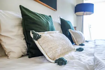a white bed with green pillows on it at Canggu Art Loft - Luxury Stay with Berawa View 2BDR in Canggu