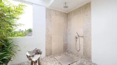 a bathroom with a shower with a stone wall at Villa Anjali Blue by Villa Finder in Seminyak