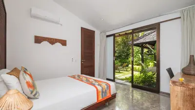 a bedroom with a bed and a sliding glass door at Villa Anjali Orange by Villa Finder in Seminyak