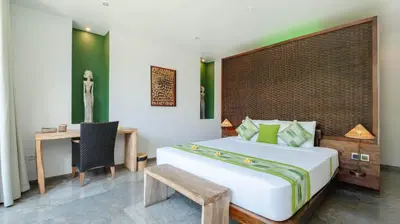 a bedroom with a bed and a table and a chair at Villa Anjali Green by Villa Finder in Seminyak