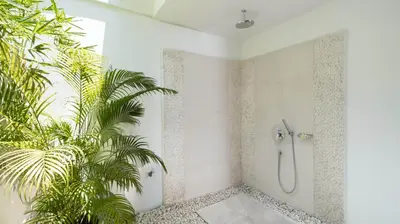 a bathroom with a shower and a palm tree at Villa Anjali Green by Villa Finder in Seminyak