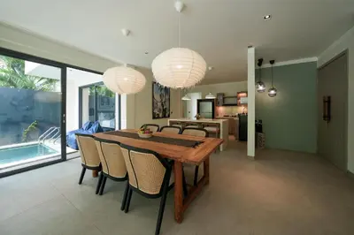 a dining room with a wooden table and chairs at Twin Villas Cora & Zeno by Exotic Bali Properties in Seminyak