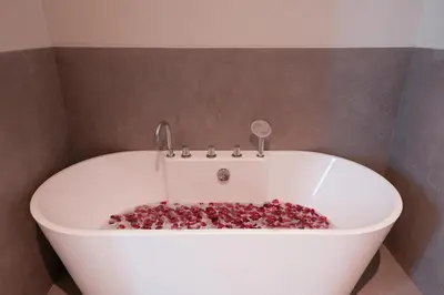 a white bath tub filled with lots of red rocks at Twin Villas Cora & Zeno by Exotic Bali Properties in Seminyak